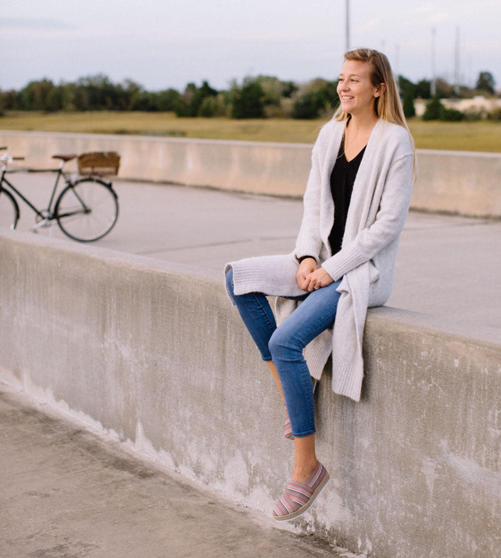 smiling woman sitting on side of road