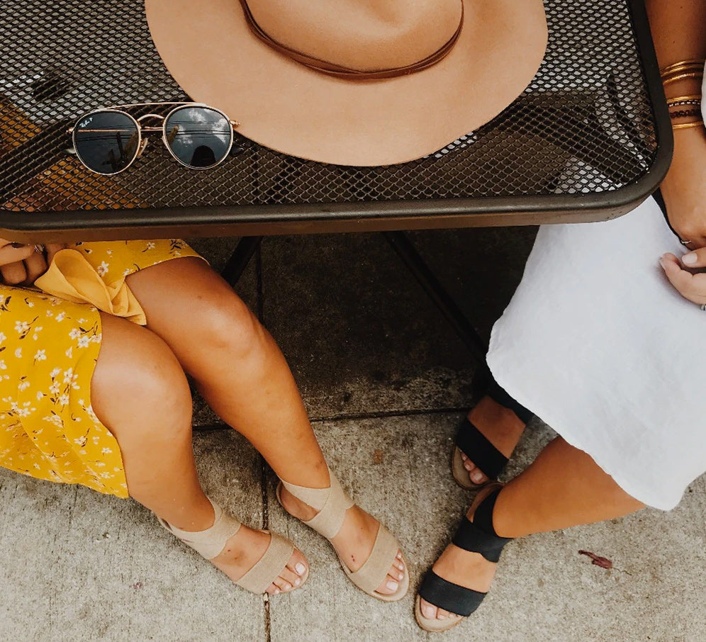 a pair of women wearing benjamin sandals sitting at a table together